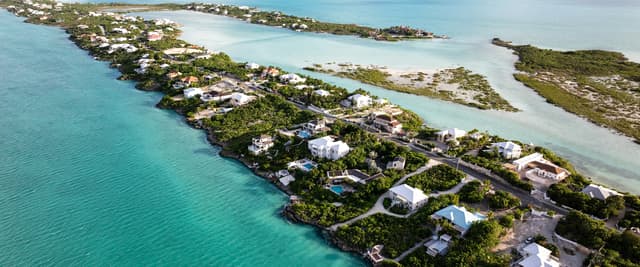 Aerial view of a narrow island with turquoise water on both sides and small coastal homes