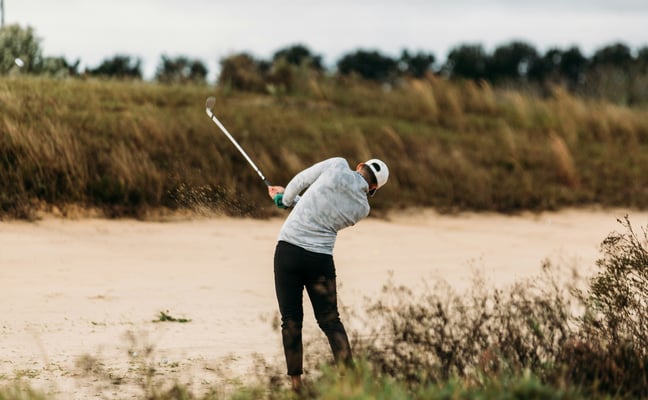 Golfer hitting out of a sand bunker